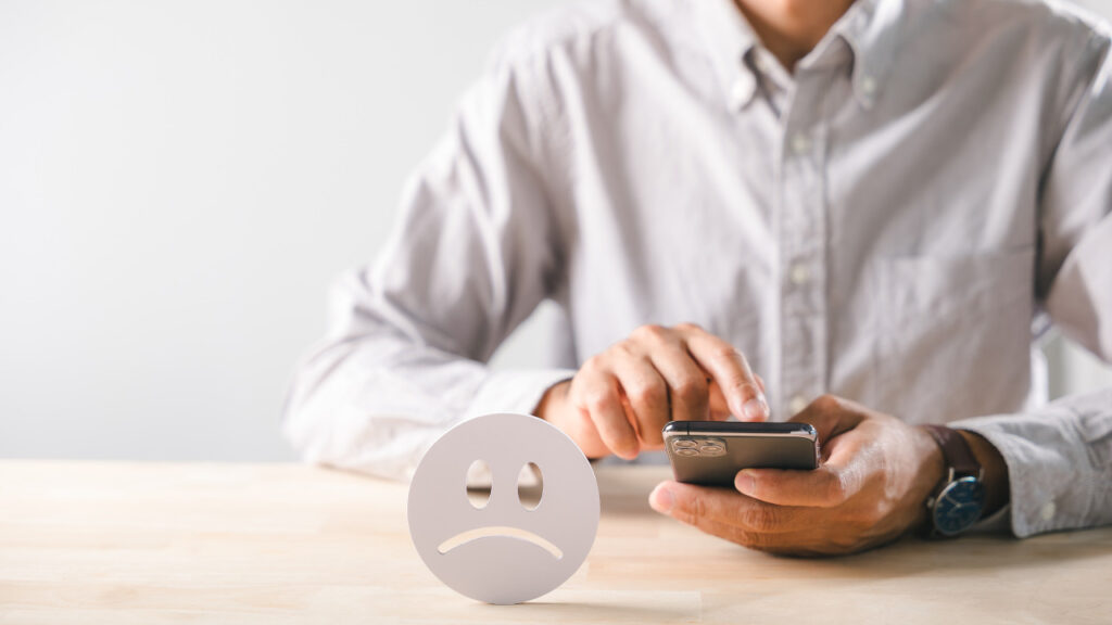 スマホを操作する人と悲しい顔の絵文字
