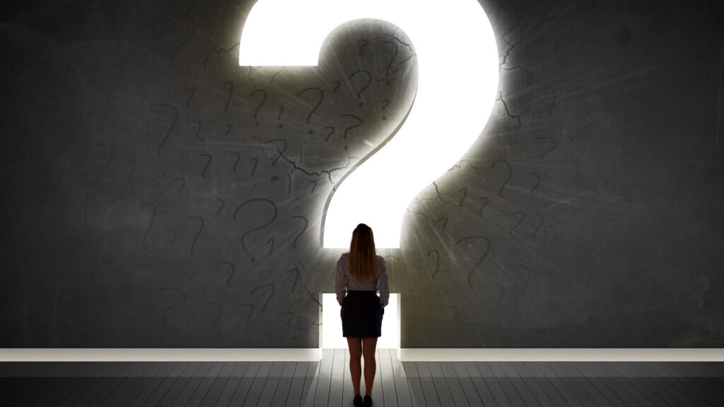 大きなはてなマークの光の前に立つ女性の後ろ姿