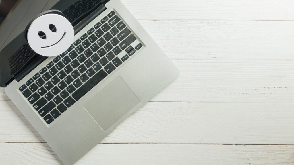 ノートパソコンの上に置かれた笑顔のスマイルマーク
