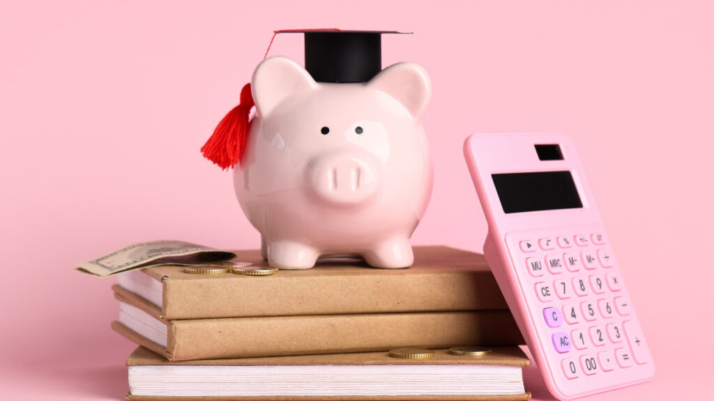 学帽をかぶった豚の貯金箱と電卓